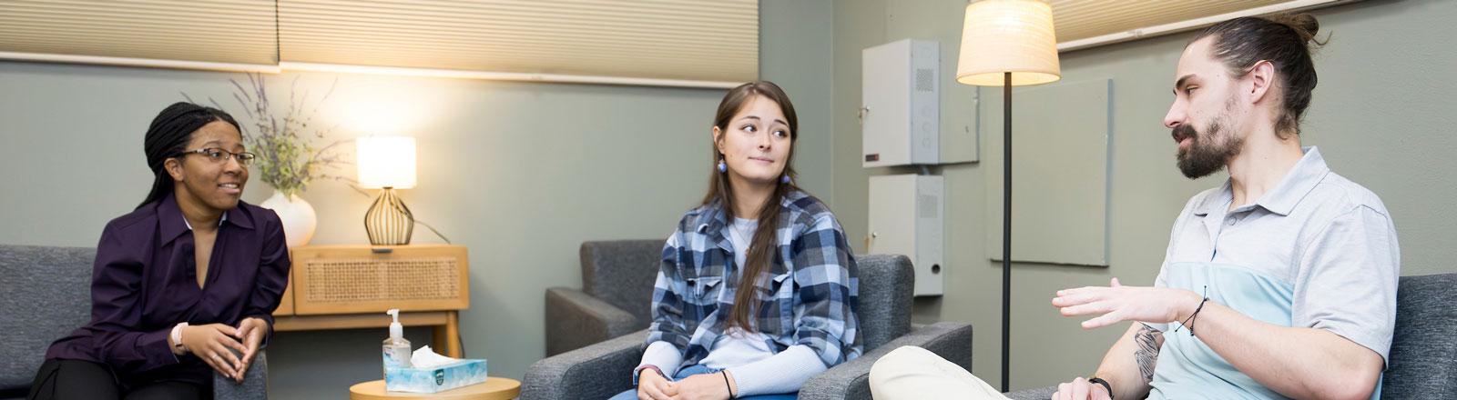 Three counseling students talking to one another in a room..